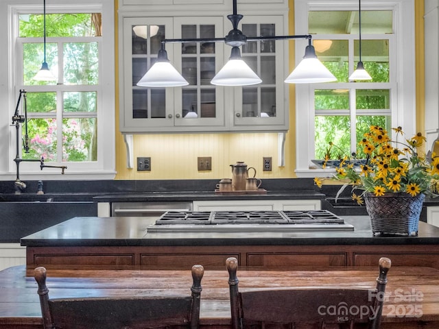 kitchen with dark countertops, glass insert cabinets, and stainless steel gas stovetop