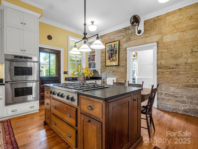 kitchen featuring dark countertops, appliances with stainless steel finishes, white cabinets, and crown molding