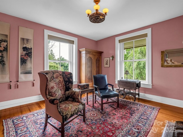 living area featuring wood finished floors, baseboards, and a chandelier