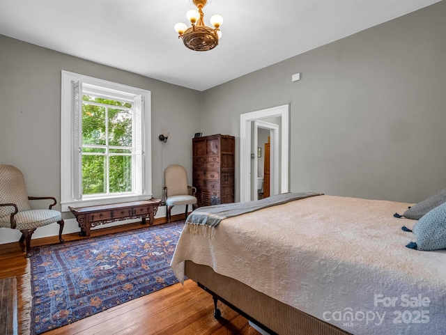 bedroom with baseboards, a notable chandelier, and wood finished floors