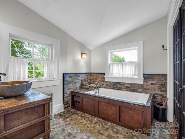 bathroom with radiator, a garden tub, vanity, and vaulted ceiling