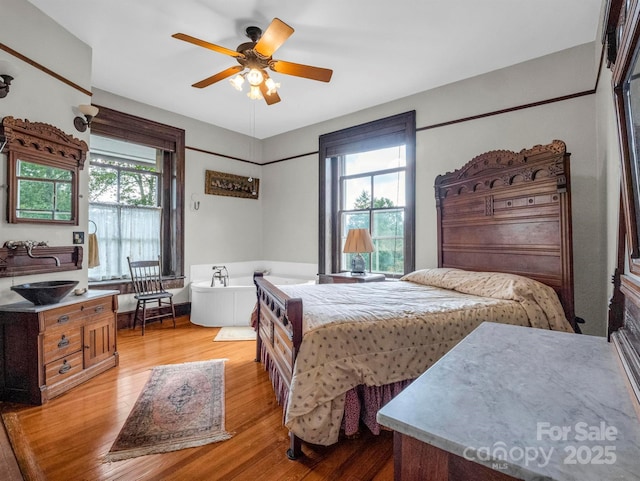 bedroom with light wood finished floors, multiple windows, and ceiling fan