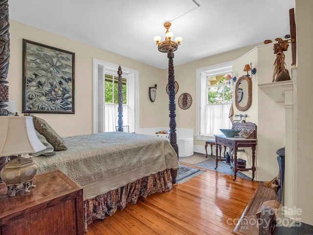 bedroom with a notable chandelier, multiple windows, and wood finished floors