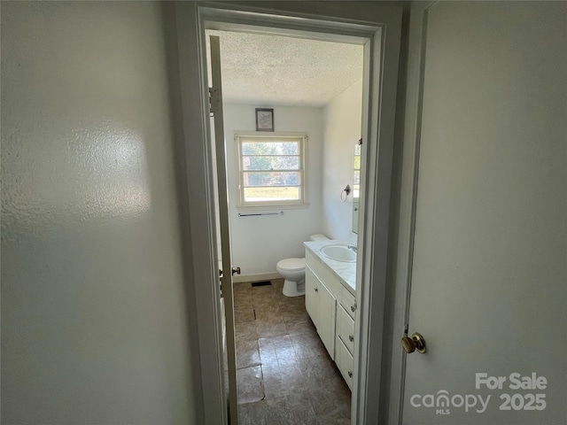 bathroom featuring toilet, visible vents, a textured ceiling, and vanity