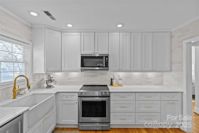 kitchen featuring a sink, visible vents, light countertops, appliances with stainless steel finishes, and tasteful backsplash