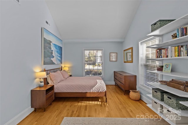 bedroom featuring light wood-style floors, visible vents, high vaulted ceiling, and baseboards