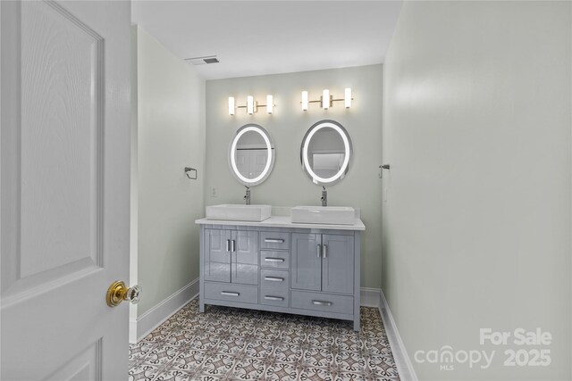 bathroom featuring tile patterned floors, a sink, baseboards, and double vanity