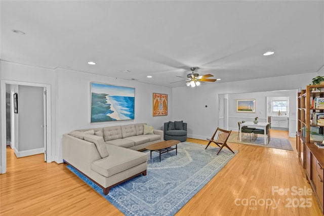 living room featuring baseboards, light wood-type flooring, a ceiling fan, and recessed lighting