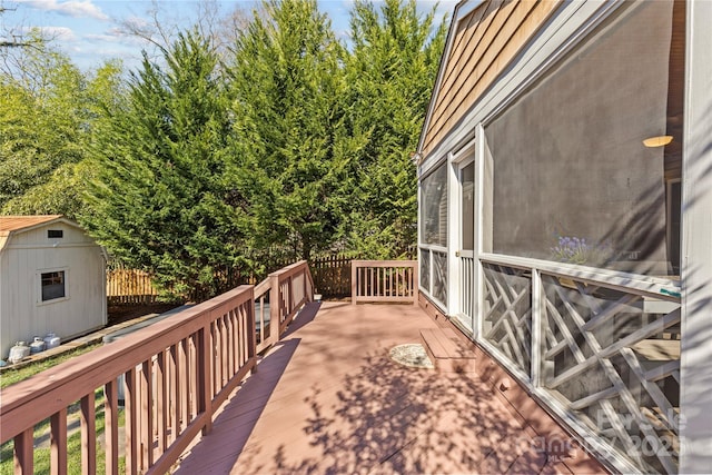 wooden terrace featuring a storage shed and an outbuilding