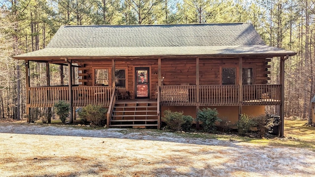 log-style house with a porch, roof with shingles, and log siding