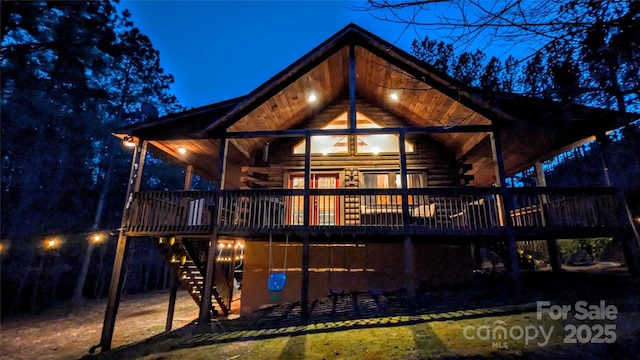 rear view of house featuring stairway, log exterior, and a deck