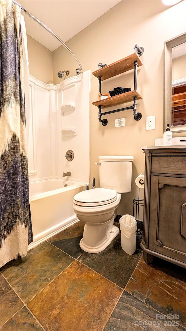 bathroom featuring washtub / shower combination, stone tile flooring, vanity, and toilet