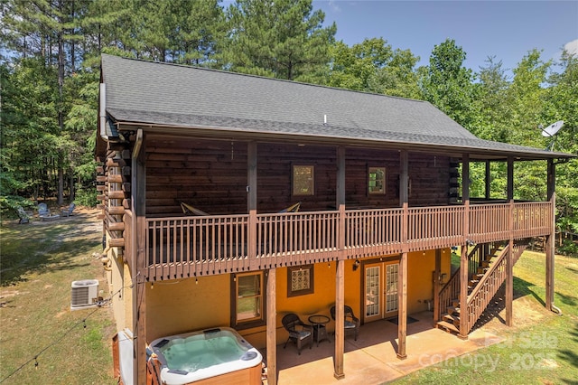 rear view of property featuring a patio, a hot tub, central AC, log siding, and a wooden deck