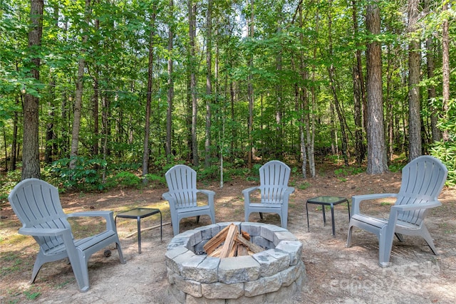 view of patio / terrace with an outdoor fire pit and a wooded view