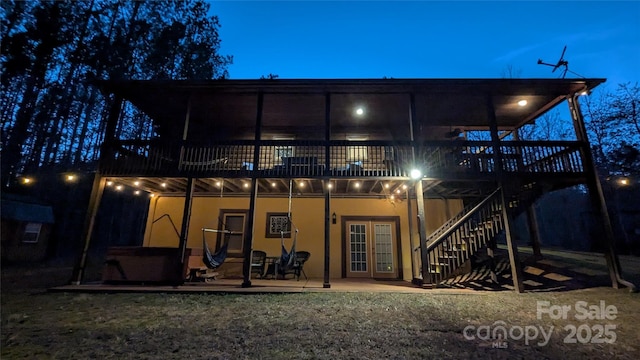 back of property with stucco siding, stairs, french doors, and a wooden deck