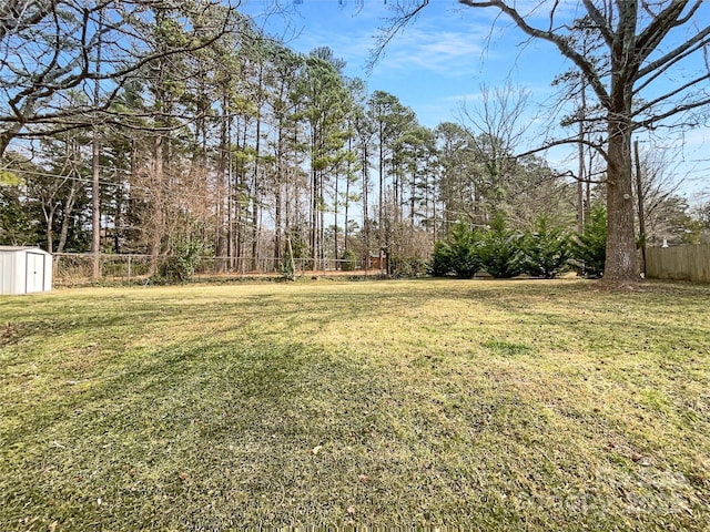 view of yard featuring a storage shed, an outdoor structure, and fence