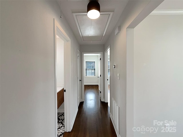 hall featuring attic access, dark wood-style flooring, and baseboards