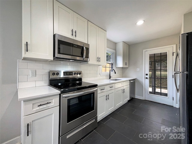 kitchen featuring a sink, white cabinets, light countertops, appliances with stainless steel finishes, and decorative backsplash