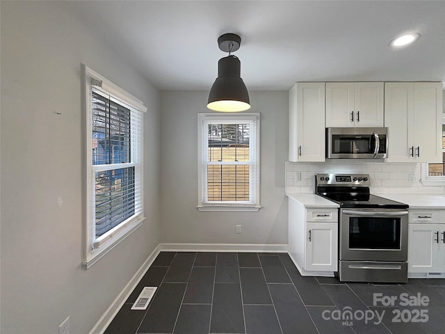 kitchen with stainless steel appliances, visible vents, baseboards, white cabinets, and backsplash