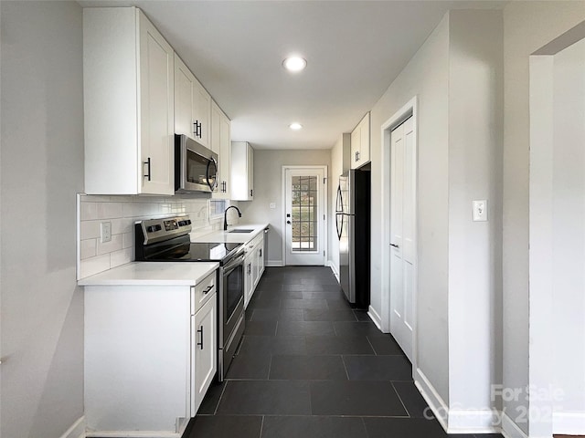 kitchen with white cabinets, appliances with stainless steel finishes, backsplash, and a sink