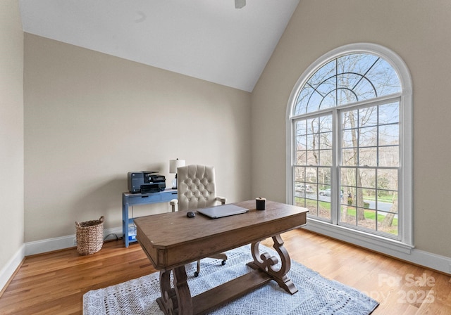 office area with baseboards, lofted ceiling, and light wood finished floors