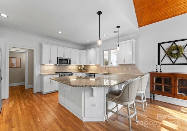 kitchen with a peninsula, light wood-style floors, tasteful backsplash, and appliances with stainless steel finishes