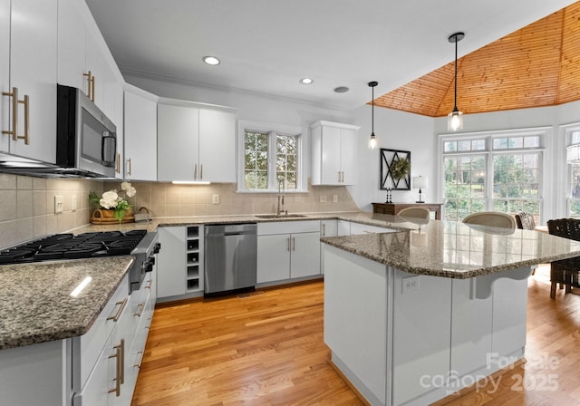 kitchen featuring light wood-type flooring, a breakfast bar, a sink, stainless steel appliances, and a peninsula