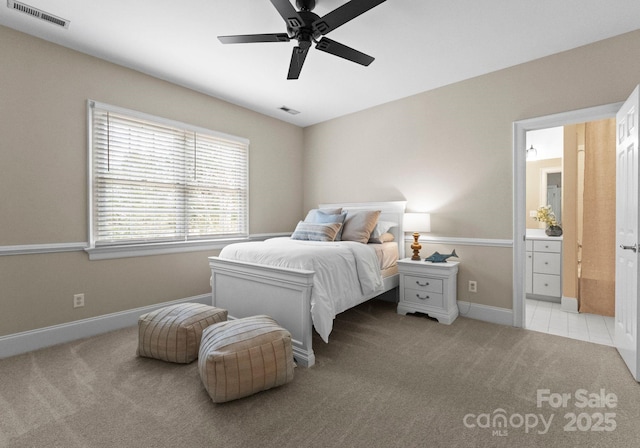 bedroom with visible vents, light carpet, baseboards, and ensuite bathroom