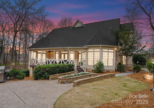 rear view of house featuring ceiling fan, a porch, fence, and a shingled roof