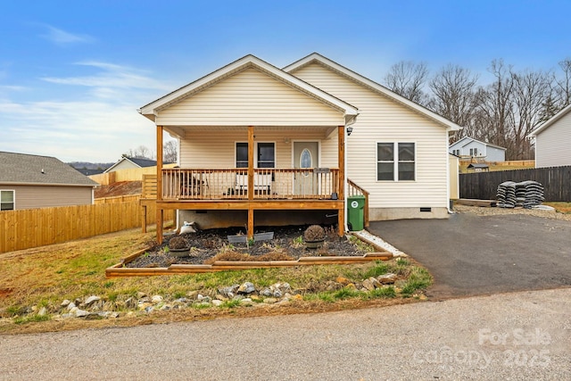 view of front facade featuring crawl space, fence, covered porch, and aphalt driveway