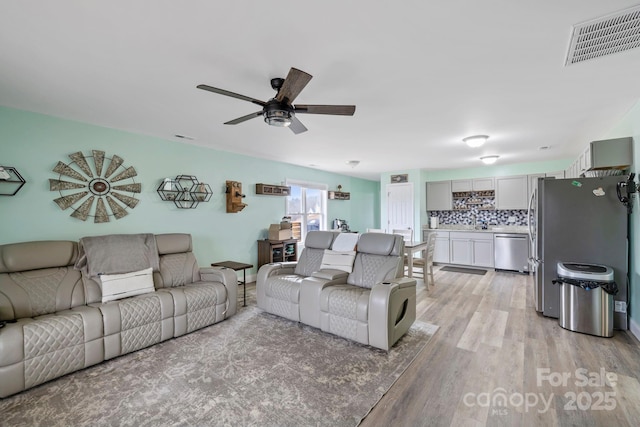 living area with light wood finished floors, visible vents, and ceiling fan