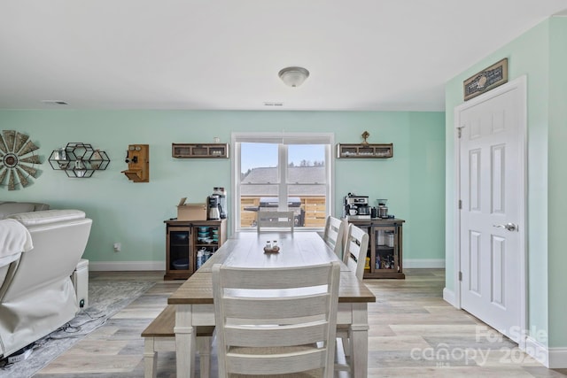 dining area with light wood-style flooring, baseboards, and visible vents