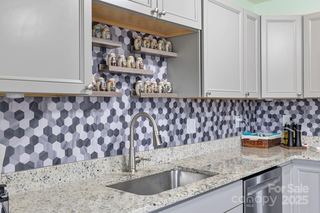 kitchen featuring open shelves, light stone countertops, backsplash, and a sink