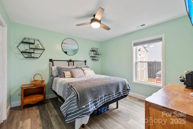 bedroom featuring ceiling fan, wood finished floors, visible vents, and baseboards