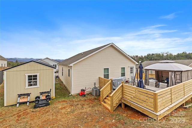 back of property featuring central AC unit, a shed, a wooden deck, a gazebo, and an outdoor structure