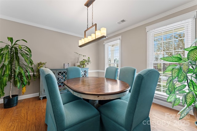 dining room with visible vents, baseboards, ornamental molding, light wood-type flooring, and an inviting chandelier