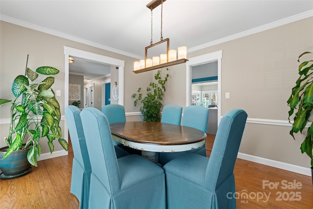 dining area with light wood-style floors, ornamental molding, and baseboards