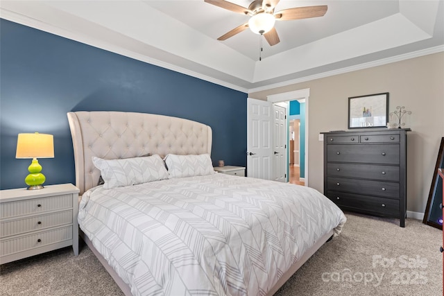 carpeted bedroom with ceiling fan, baseboards, and a raised ceiling