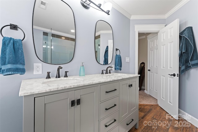 bathroom featuring visible vents, ornamental molding, a sink, and wood finished floors