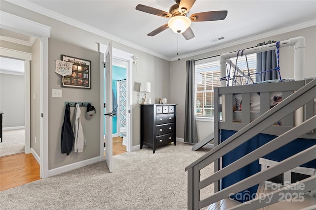 carpeted bedroom featuring visible vents, crown molding, baseboards, and ensuite bathroom