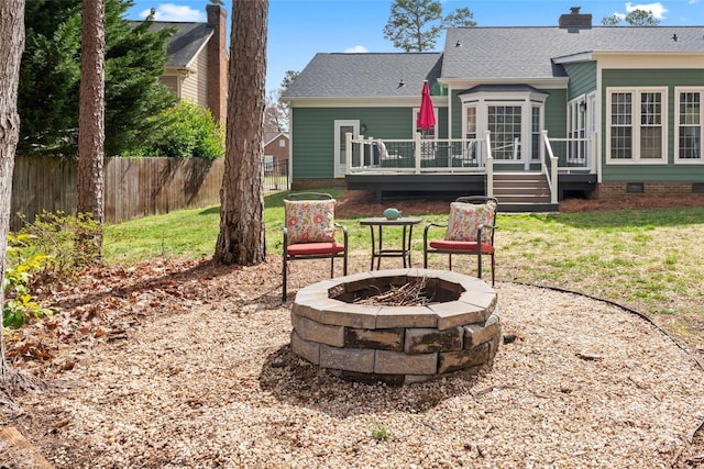 rear view of house with an outdoor fire pit, a chimney, crawl space, fence, and a wooden deck