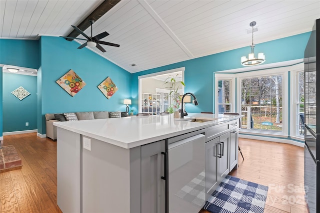 kitchen featuring open floor plan, a sink, lofted ceiling with beams, and wood finished floors