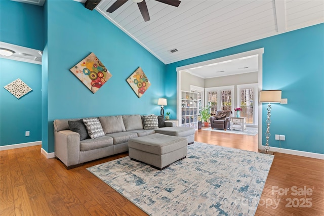 living area featuring vaulted ceiling with beams, wood finished floors, visible vents, baseboards, and crown molding