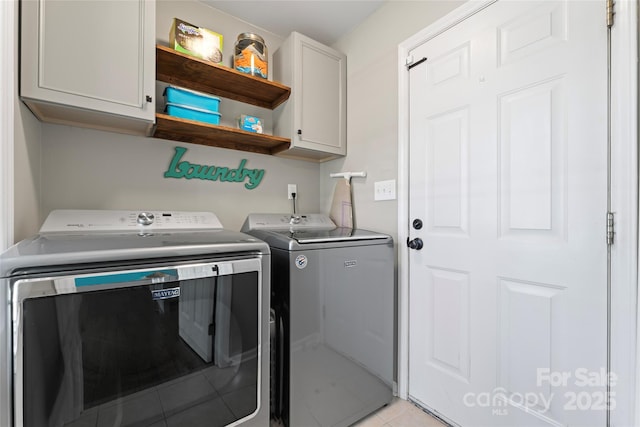 laundry area featuring cabinet space, washing machine and clothes dryer, and light tile patterned floors