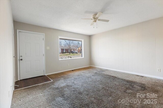 unfurnished room featuring ceiling fan, carpet, visible vents, and a textured ceiling