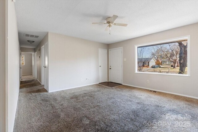 carpeted spare room featuring visible vents, baseboards, and a textured ceiling