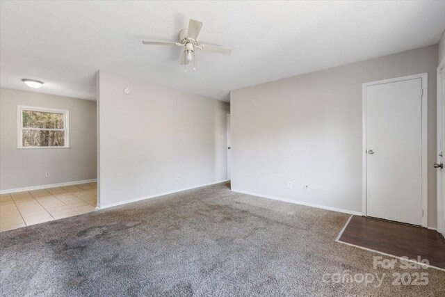 carpeted empty room with a textured ceiling, baseboards, and ceiling fan