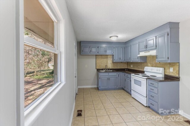 kitchen featuring white electric range, under cabinet range hood, a sink, dark countertops, and decorative backsplash