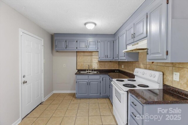 kitchen featuring dark countertops, backsplash, under cabinet range hood, white electric range oven, and a sink