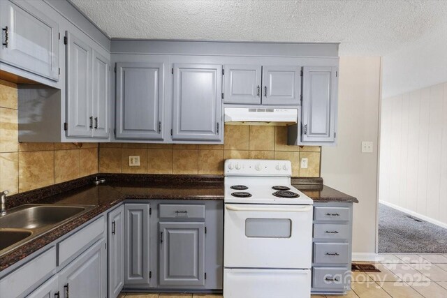 kitchen with dark countertops, under cabinet range hood, decorative backsplash, gray cabinets, and electric range